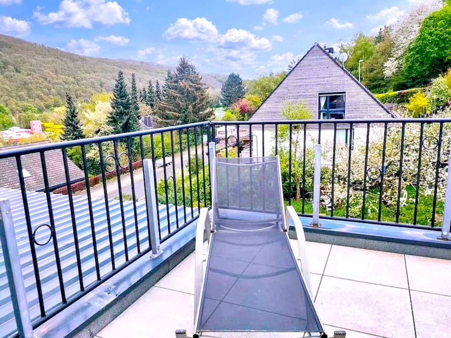 Sonnige Terrasse mit Liegestuhl und Blick ins Grüne